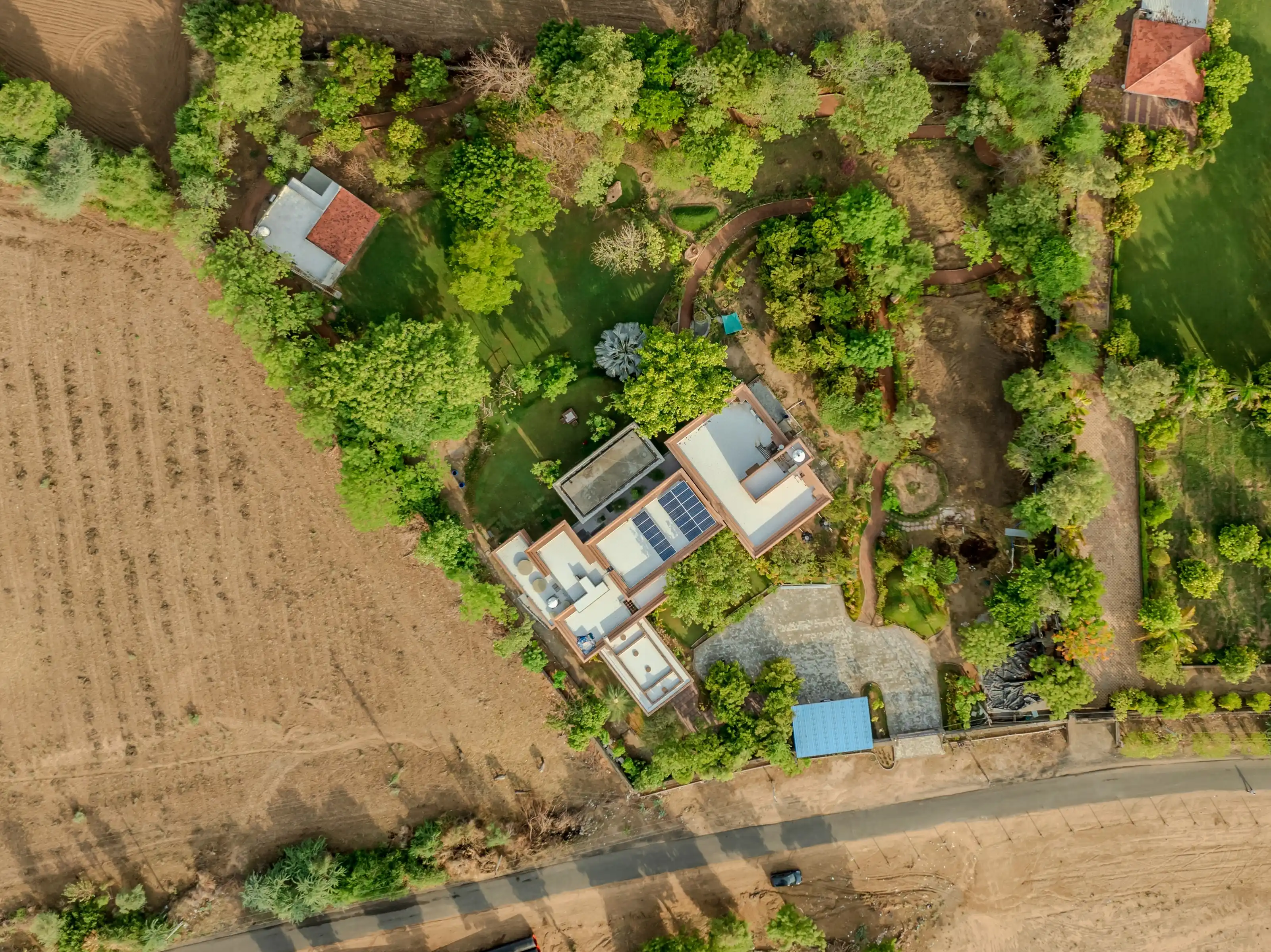 Top-down aerial of the house, its grove and the surrounding fields at the end of the day
