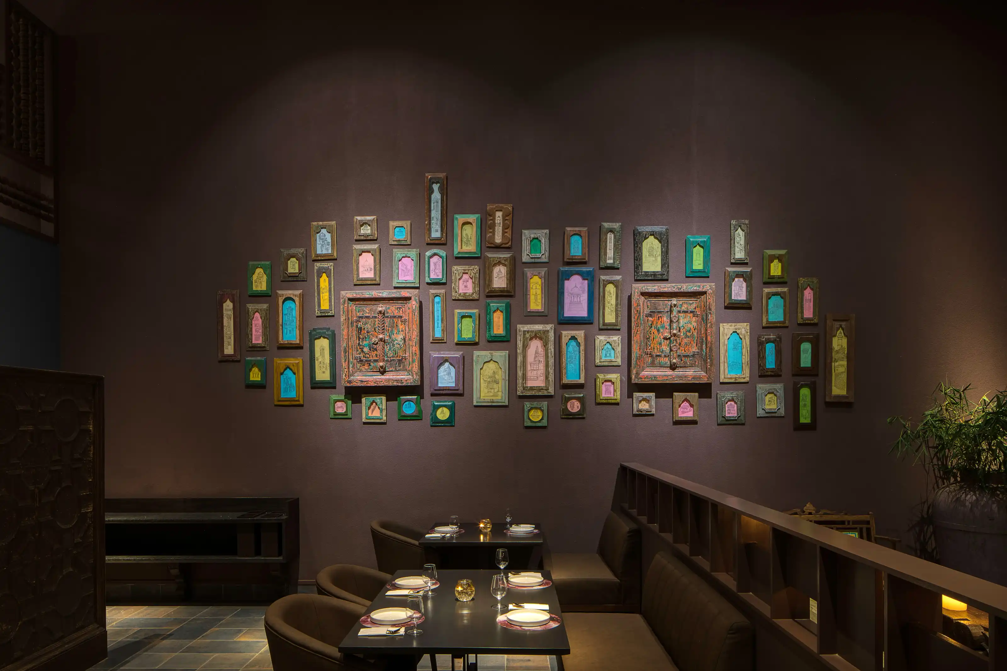 Wide view of the gallery wall filled with small colourful framed architectural fragments above the dining booths