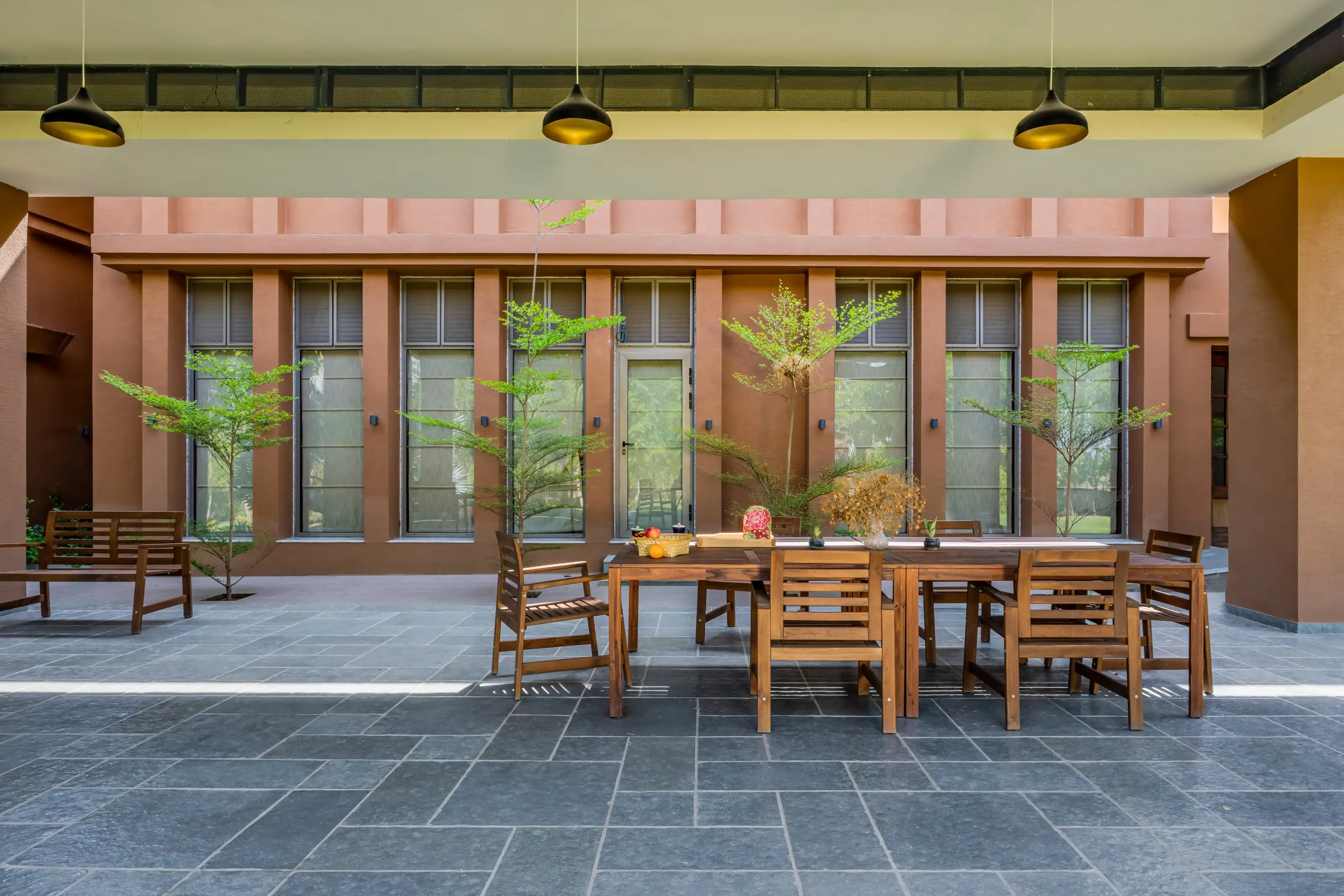 Covered outdoor dining terrace with folding glass doors behind a screen of window shutters