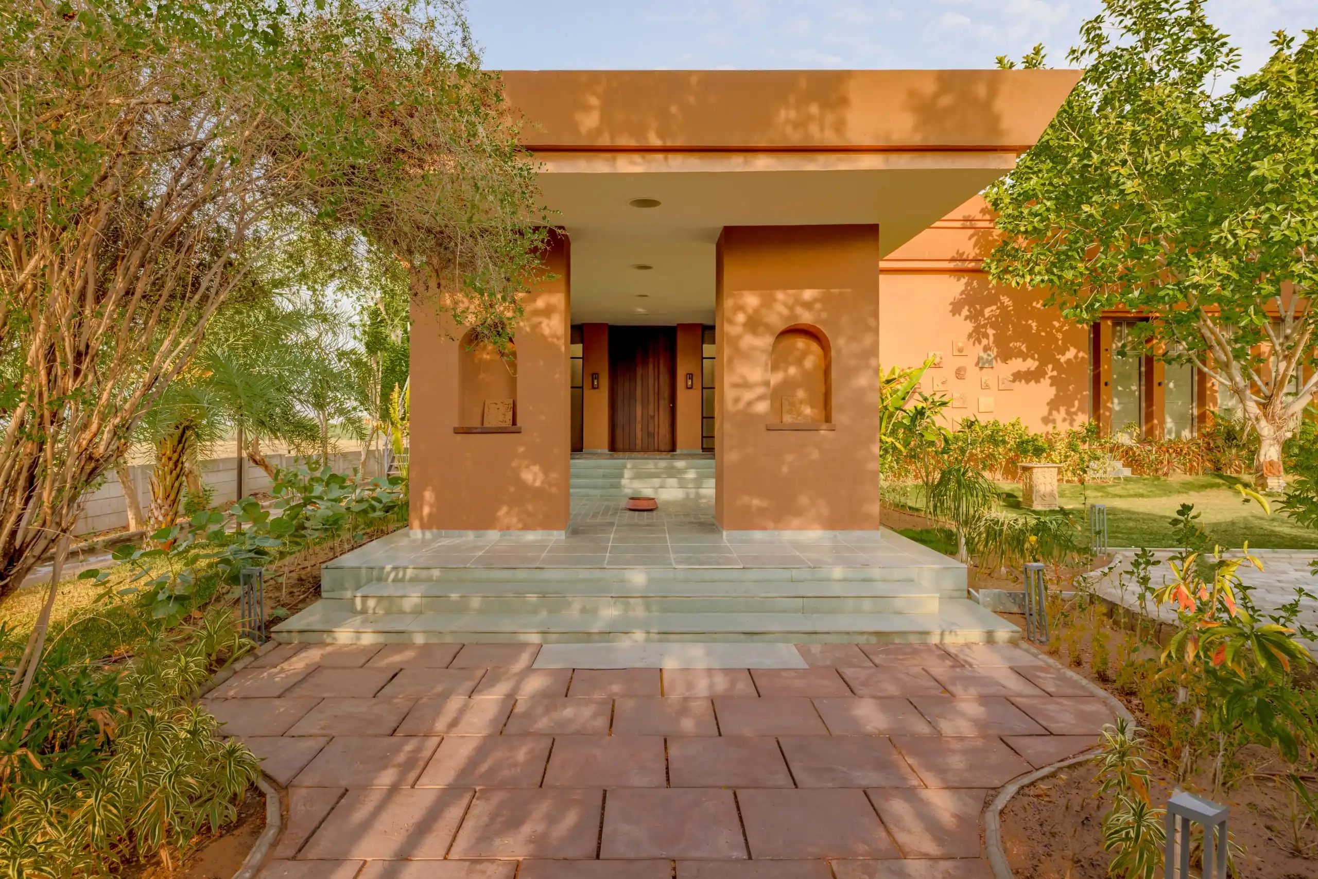 Ochre entrance portico of a single-storey farmhouse in low afternoon sun