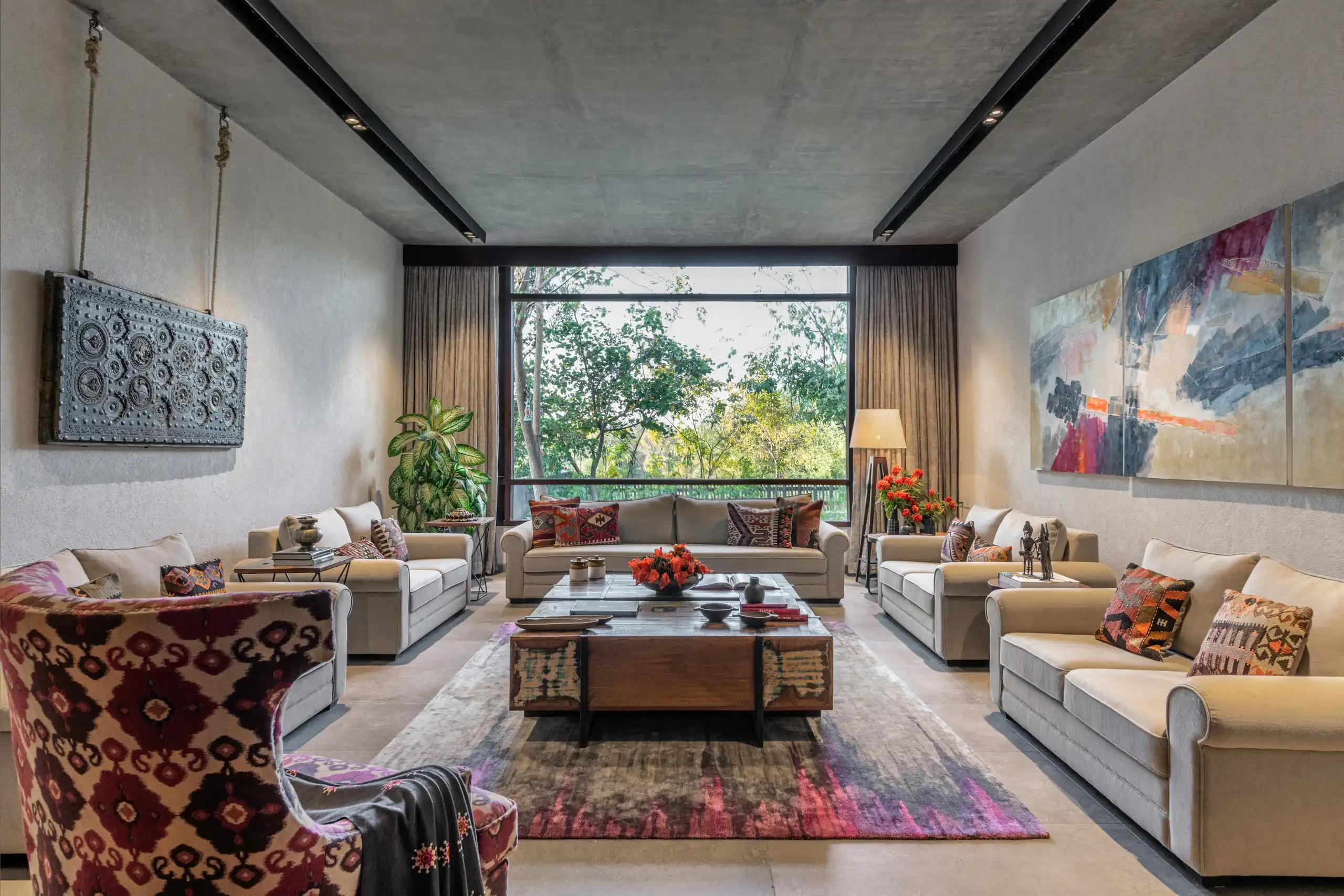 Living room beneath a cast concrete ceiling plane, opening to trees through a full-height window