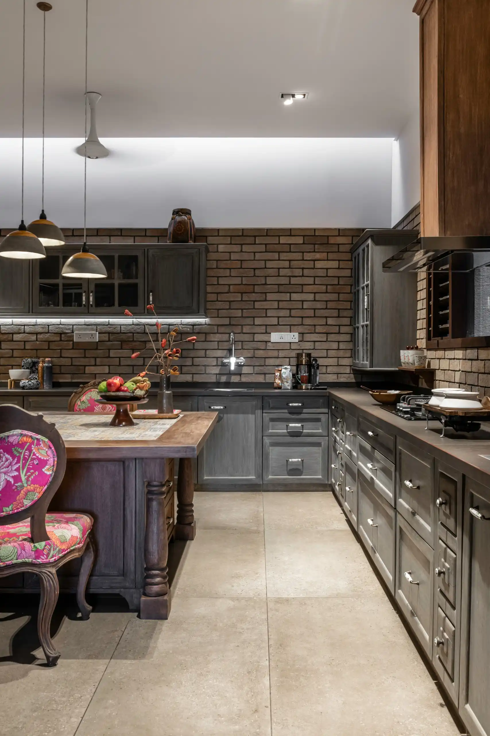 Dark timber kitchen joinery against exposed brick and a polished stone floor