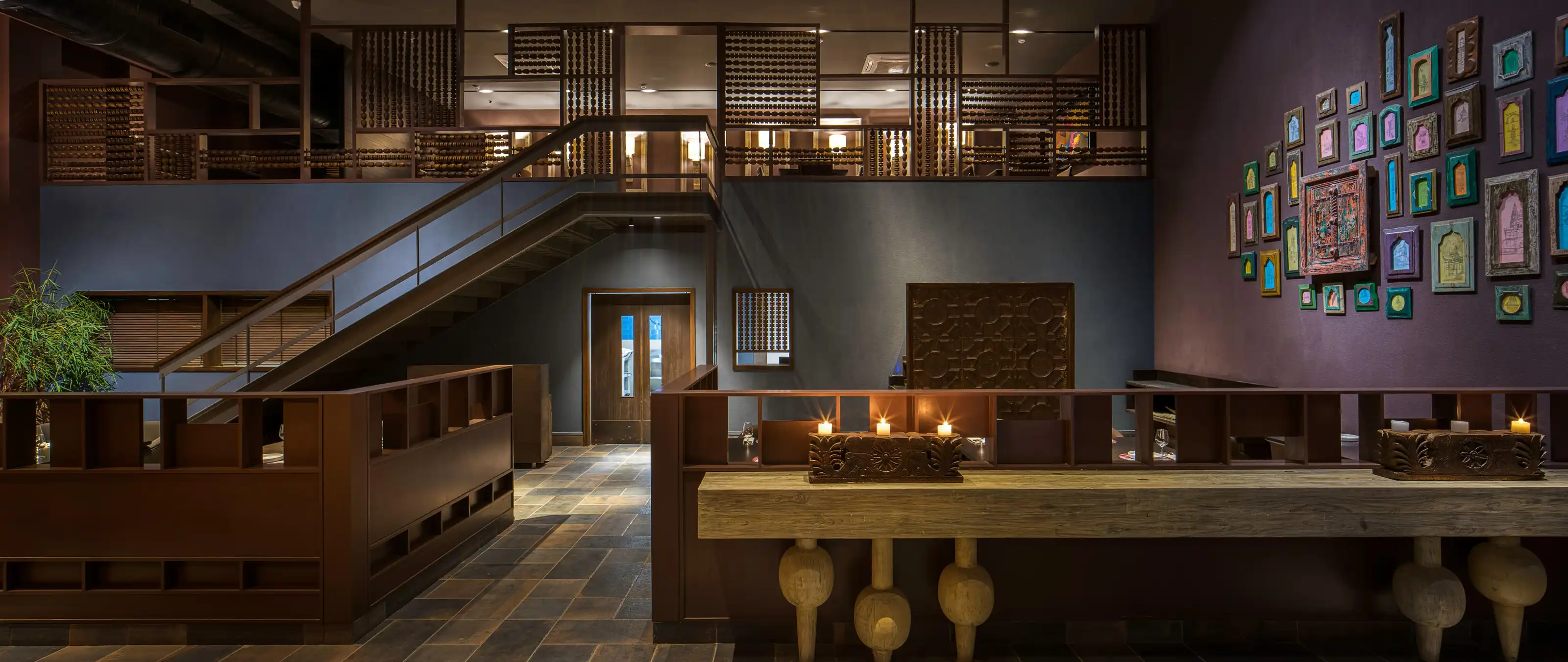 Double-height dining volume lit by candlelight and brass