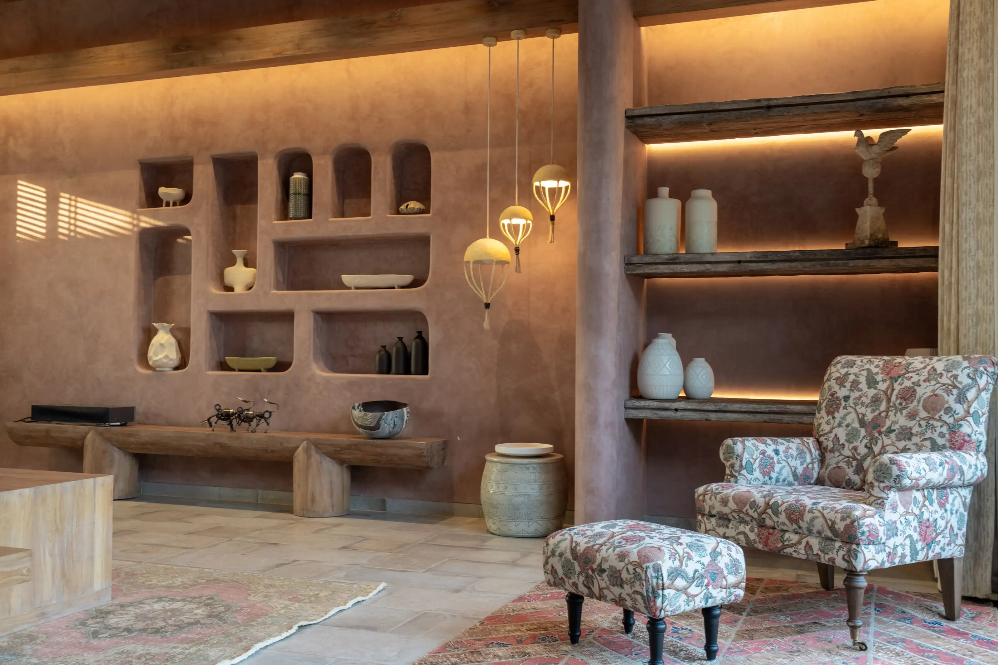 Terracotta living room with recessed ceramic display niches, hanging balloon pendant lights and a floral armchair