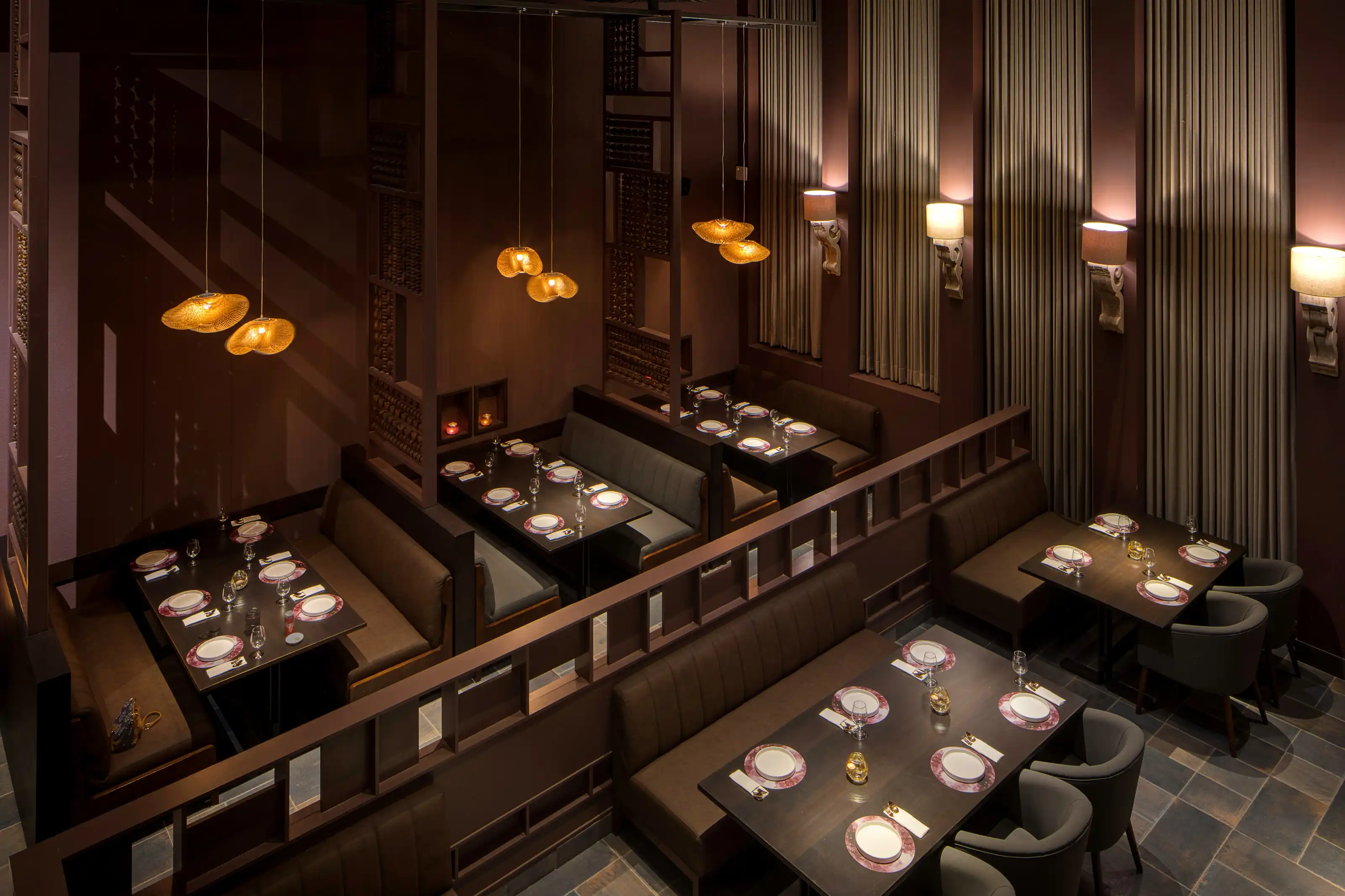 Restaurant booths in dark timber and charcoal upholstery beneath brass pendant lamps