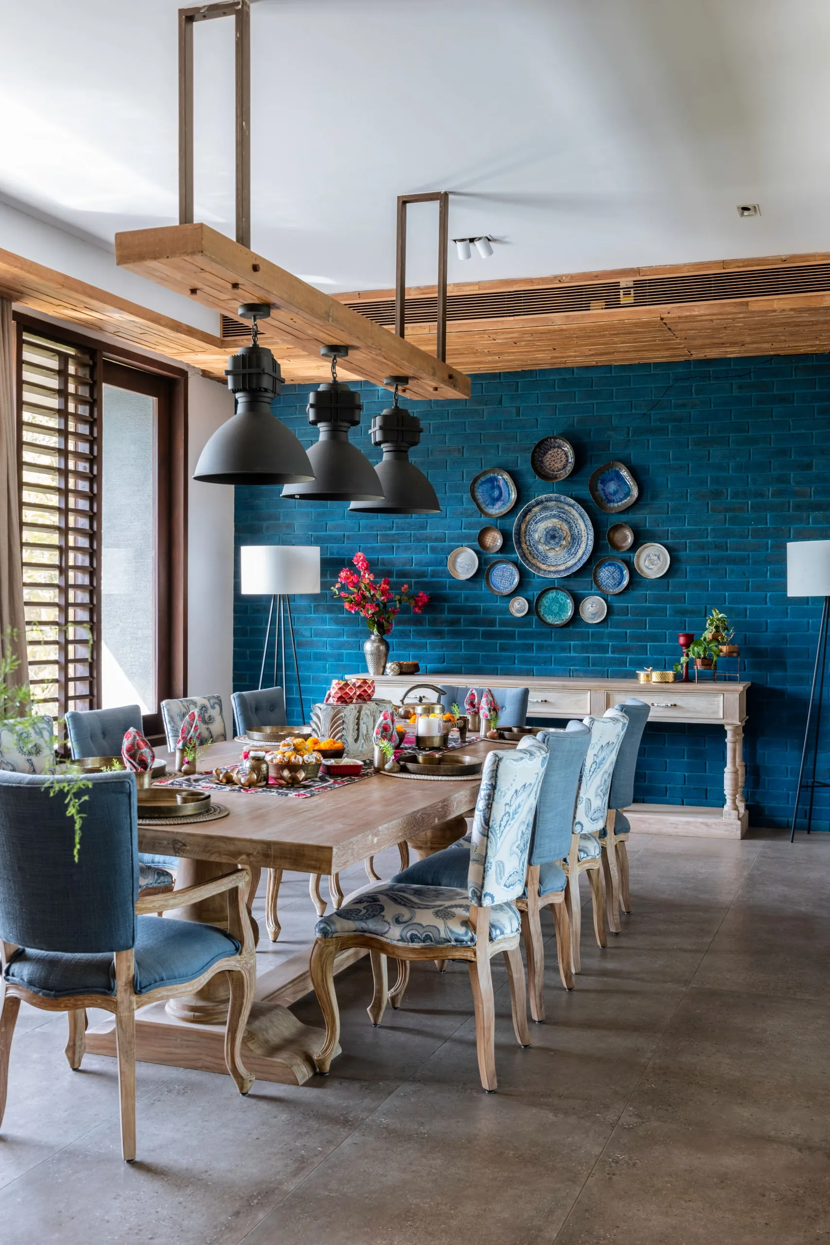 Dining room with a teal brick wall hung with a circular arrangement of ceramic plates