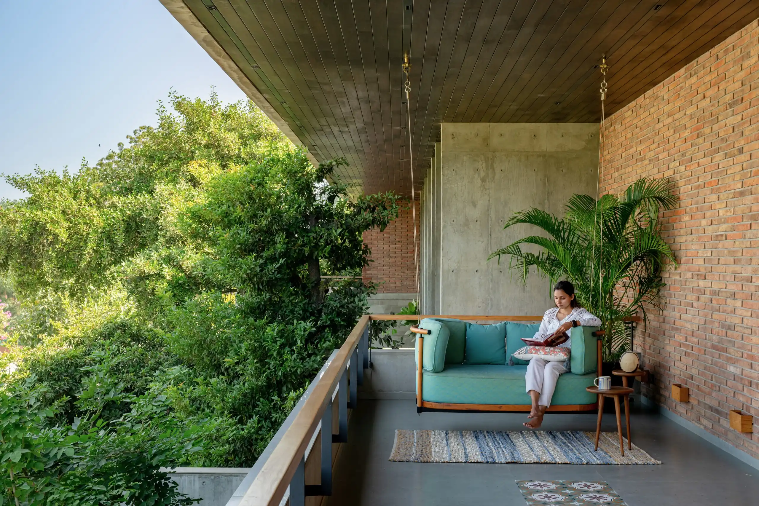 Verandah with hanging swing beneath a board-formed concrete soffit
