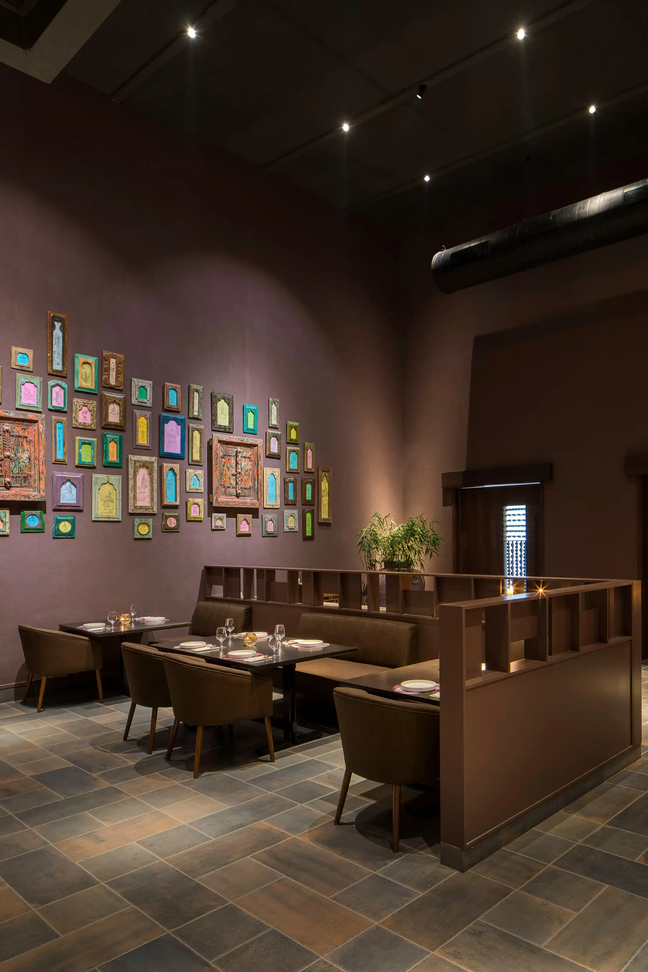 Detail of the mauve gallery wall hung with dozens of small colourful framed pieces